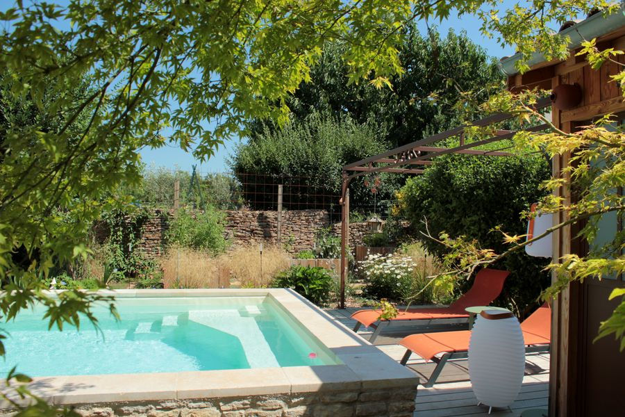 Photo de la réalisation d'une piscine semi enterrée, habillage pierre naturelle, pour bassin d'agrément et un jardin naturel près de Mâcon.