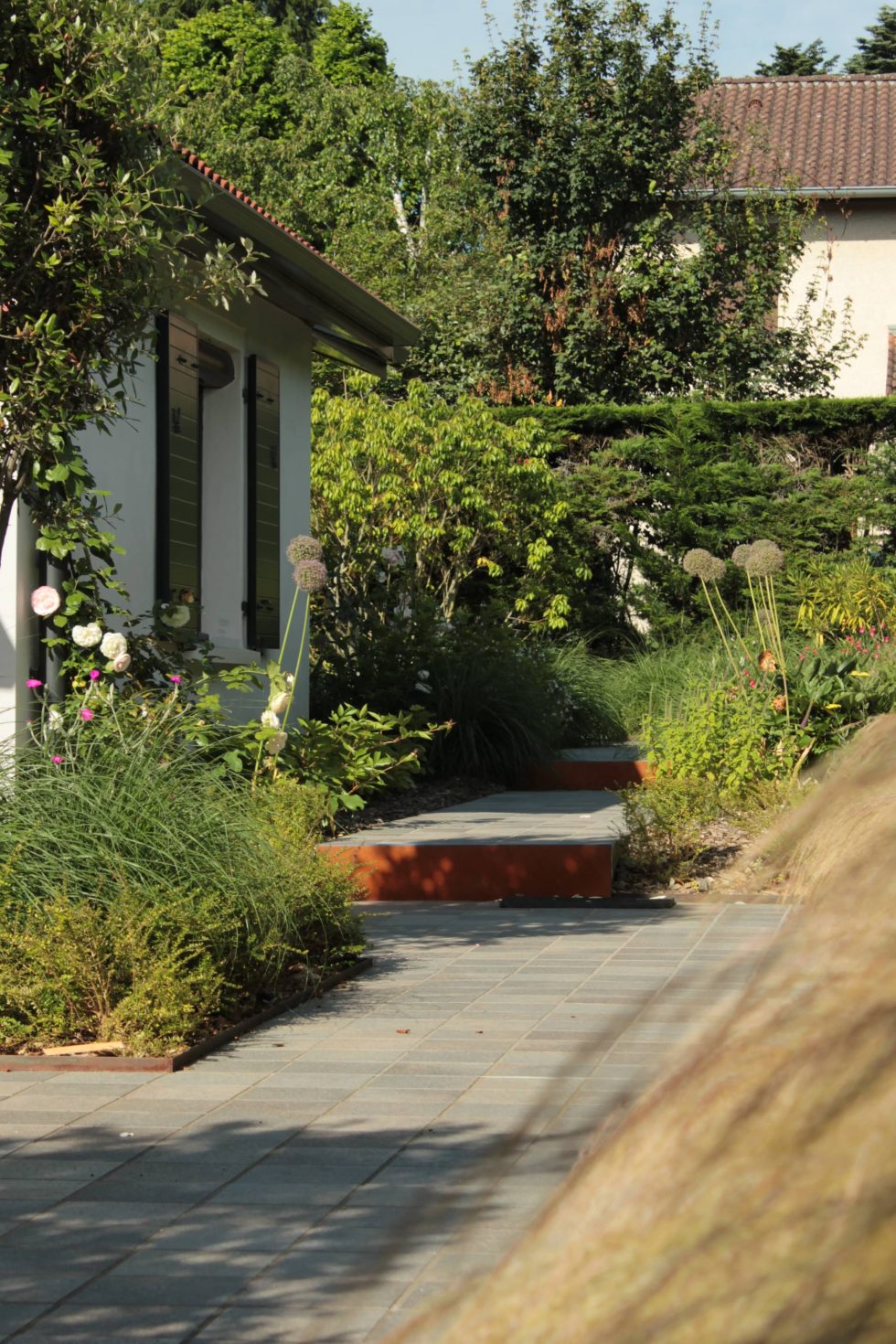 photo du réaménagement d'un jardin à Saint Didier au Mont d'Or. Création de carrés plantés : des plantations luxuriantes dans des lignes droites. Nous avons profité des légères différences de niveau pour créer un allée bordée de végétation et ponctuée de quelques marches.