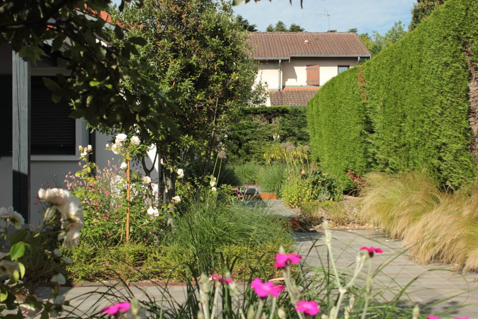 photo du réaménagement d'un jardin à Saint Didier au Mont d'Or. Création de carrés plantés : des plantations luxuriantes dans des lignes droites. Nous avons profité des légères différences de niveau pour créer un allée bordée de végétation et ponctuée de quelques marches. Carreaux petits formats au teintes douces et discrètes, contrastant avec les plantations variées.