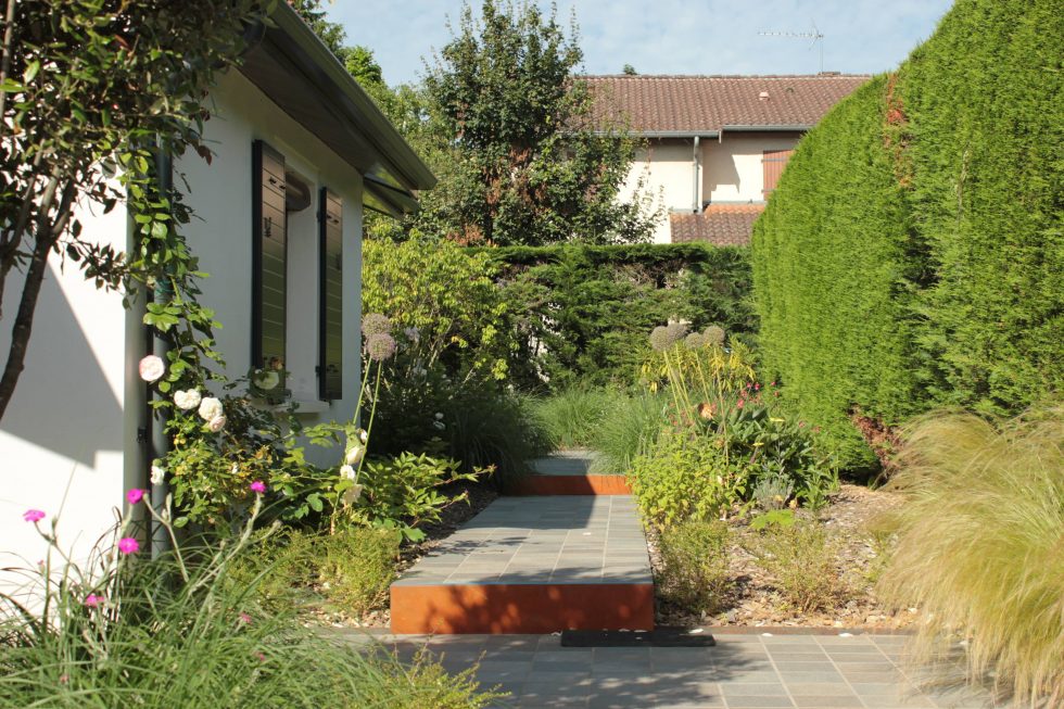 photo du réaménagement d'un jardin à Saint Didier au Mont d'Or. Création de carrés plantés : des plantations luxuriantes dans des lignes droites. Nous avons profité des légères différences de niveau pour créer un allée bordée de végétation et ponctuée de quelques marches.