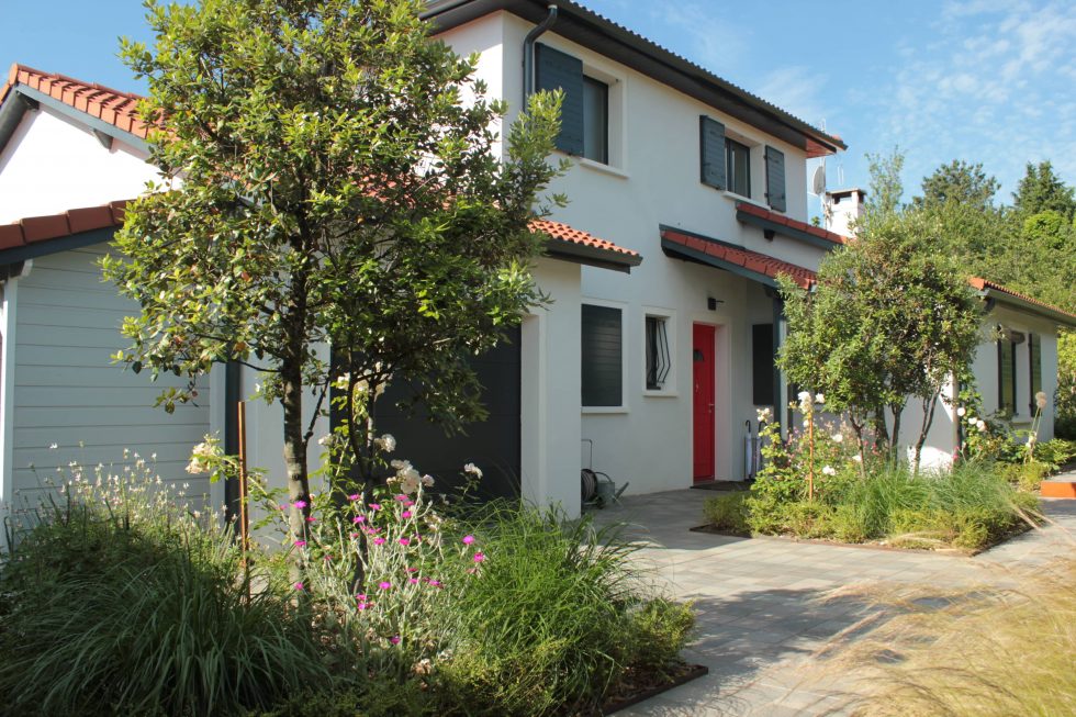 Photo de la cour et accès de cette maison à Saint Didier au Mont d'Or : carreaux petits formats aux teintes nordiques, mis en valeurs par deux grands carrés plantés. Cet aménagement offre une arrivée accueillante et vivante, à pied ou en voiture.