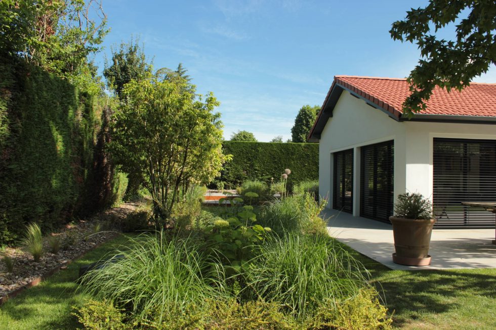 photo du réaménagement d'un jardin à Saint Didier au Mont d'Or. Création de carrés plantés : des plantations luxuriantes dans des lignes droites. Nous avons profité des légères différences de niveau pour créer un allée ponctuée de quelques marches. Extension de l'habitation.