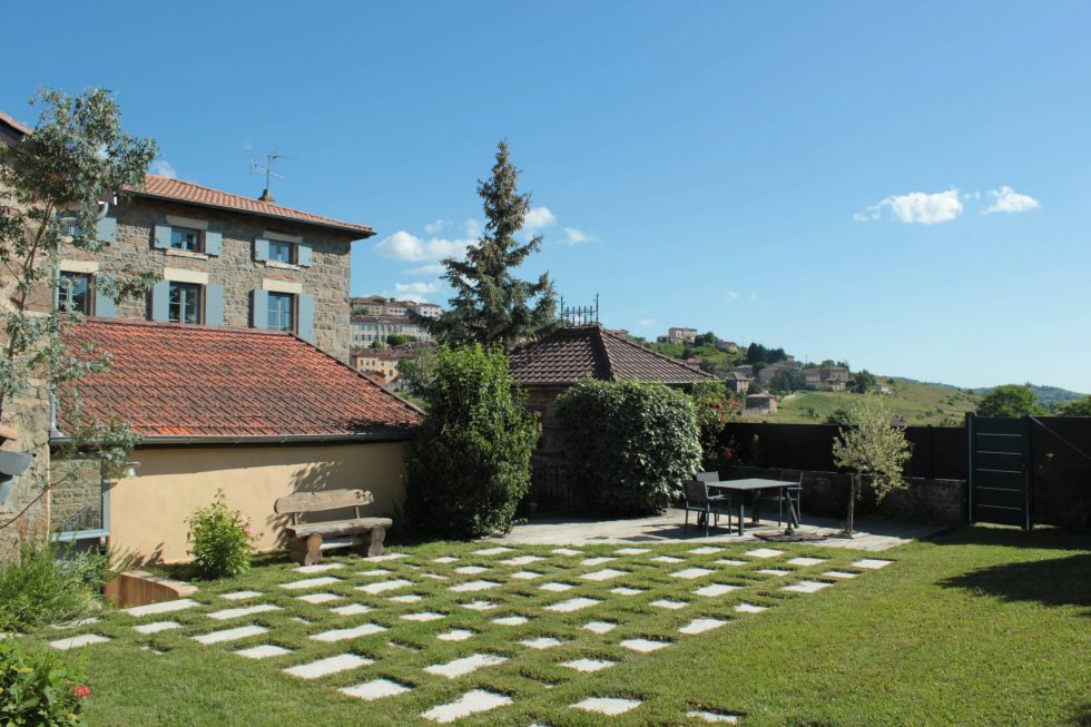 Photos d'une terrasse réalisée en dalles de pierre, clairsemées dans le gazon, pour un espace naturel et invitant à la terrasse en bois. A vaux-en-Beaujolais.