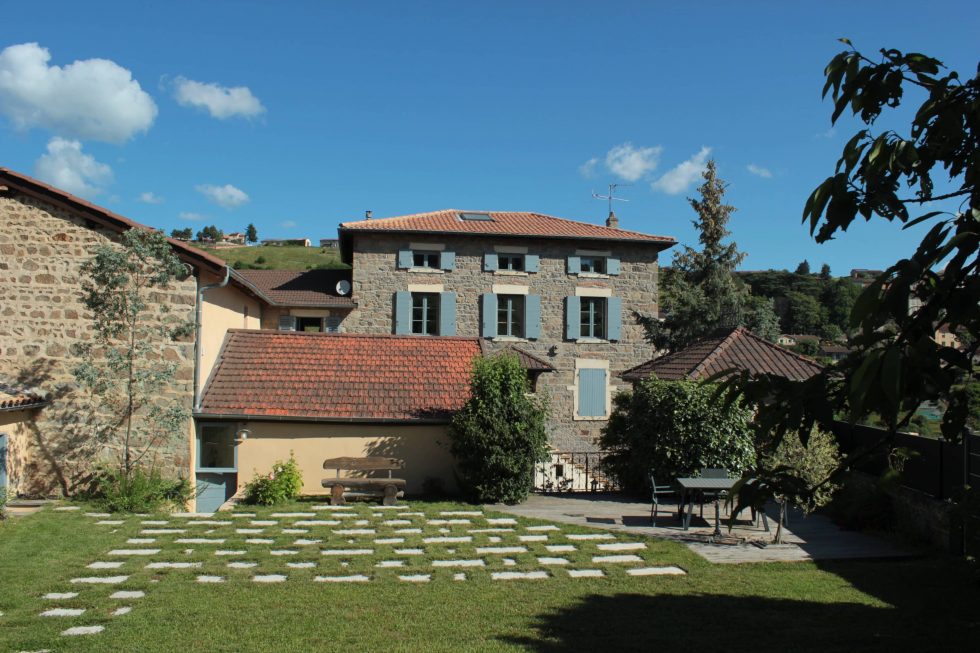 Photos d'une terrasse réalisée en dalles de pierre, clairsemées dans le gazon, pour un espace naturel et invitant à la terrasse en bois. A vaux-en-Beaujolais.