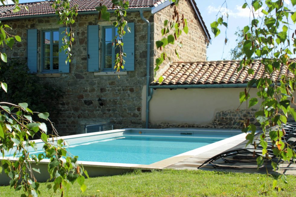 Photo d'une piscine semi-enterrée, réalisée dans un grand jardin nature, dans le Beaujolais, avec plage en bois