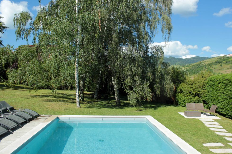 Photo d'une piscine semi-enterrée, avec sa plage réalisée en bois et sa vue sur le paysage, à Vaux en Beaujolais.