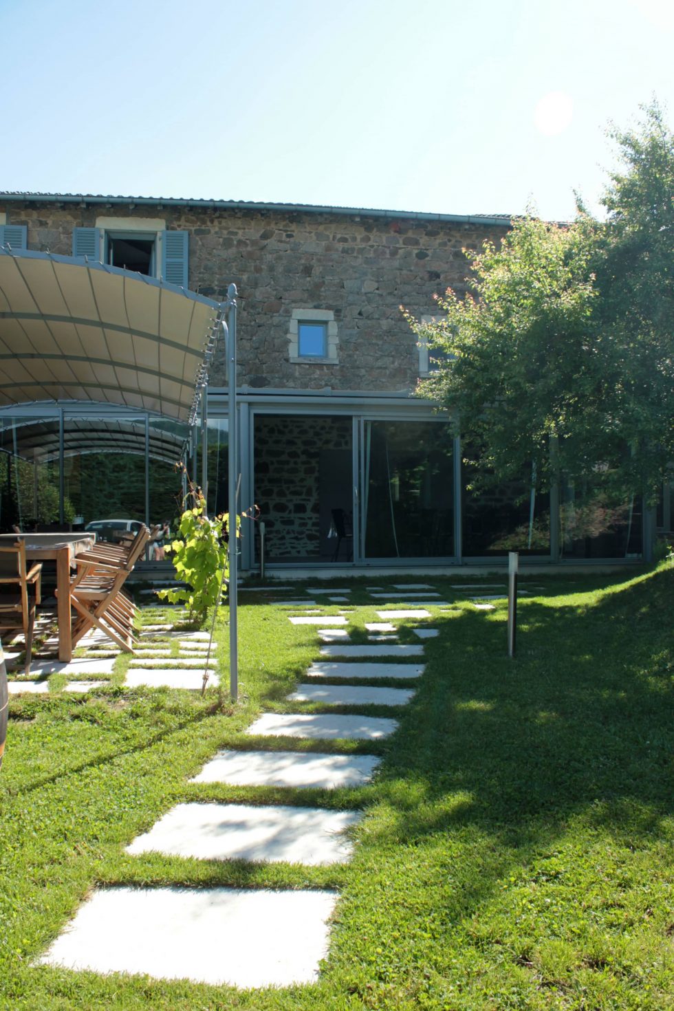 Allée en dalles de pierre, joints gazon, pour un accès au gîte naturel et pratique.